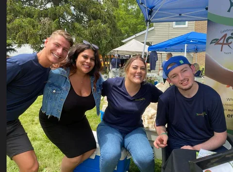 Hopewell staff in team shirts sitting together under tents at an outdoor summer event