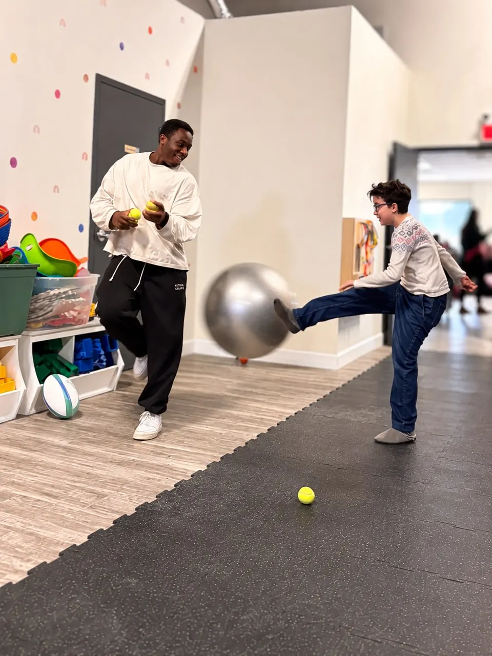 A staff member and a young person playing an energetic ball game together indoors