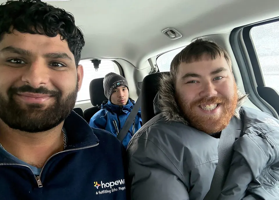 A Hopewell staff member and supported individuals smiling together for a selfie on a drive