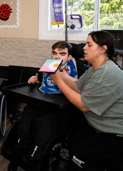 A support worker and a young man looking together at a painting he has just finished
