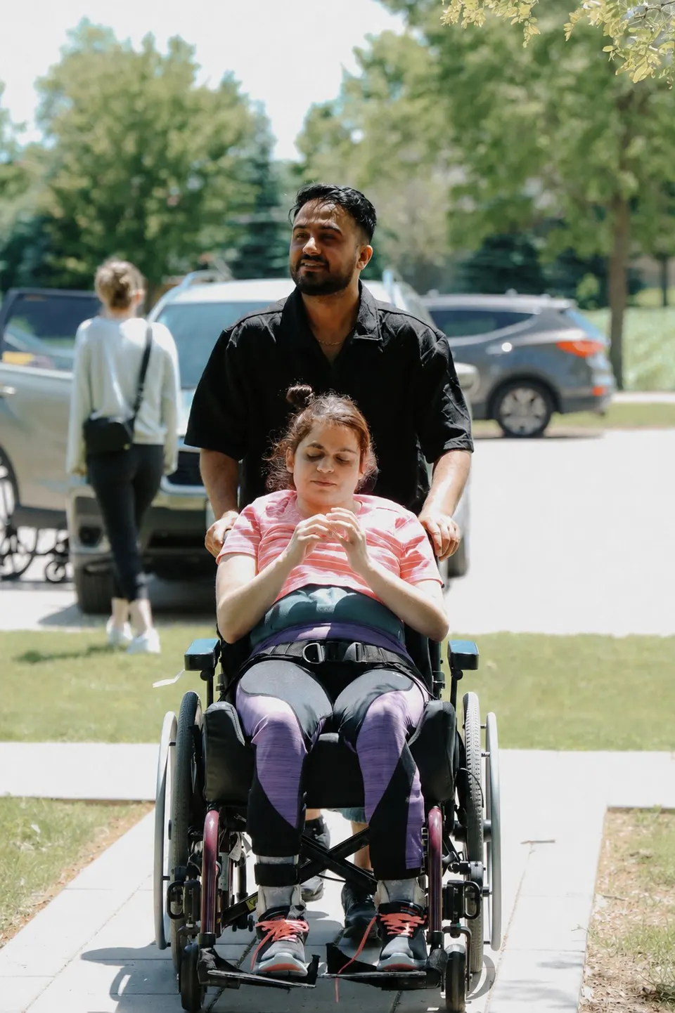 A woman being pushed in her wheelchair through a community event on a summer day