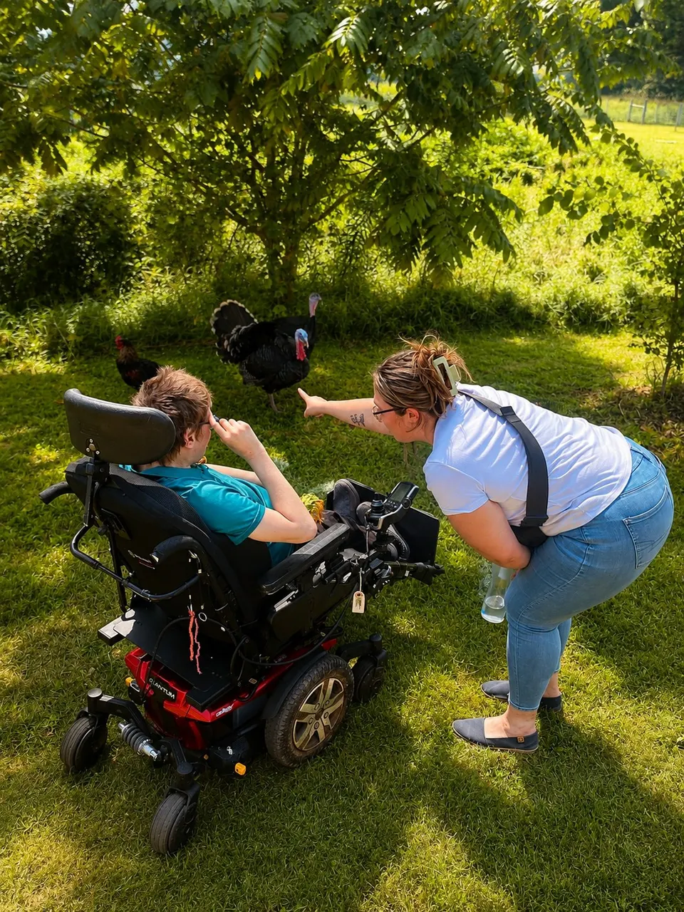 A supported individual meeting a turkey during a farm visit, with a staff member alongside