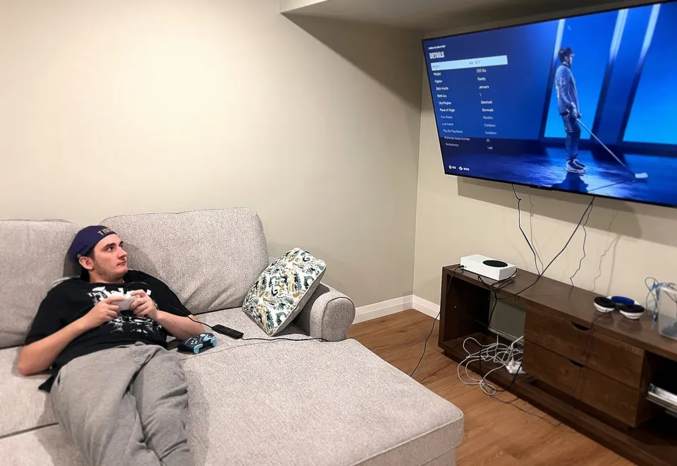 A young man relaxing on the sofa playing a video game in his living room