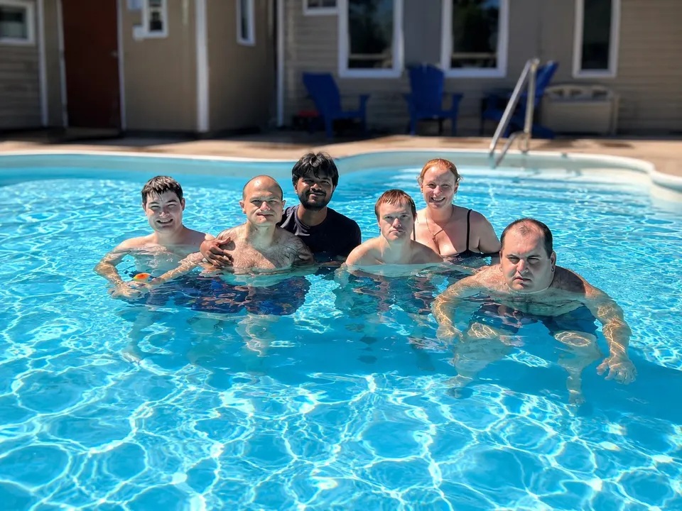 A group of men in the pool together on a Hopewell Connect swim day, smiling at the camera