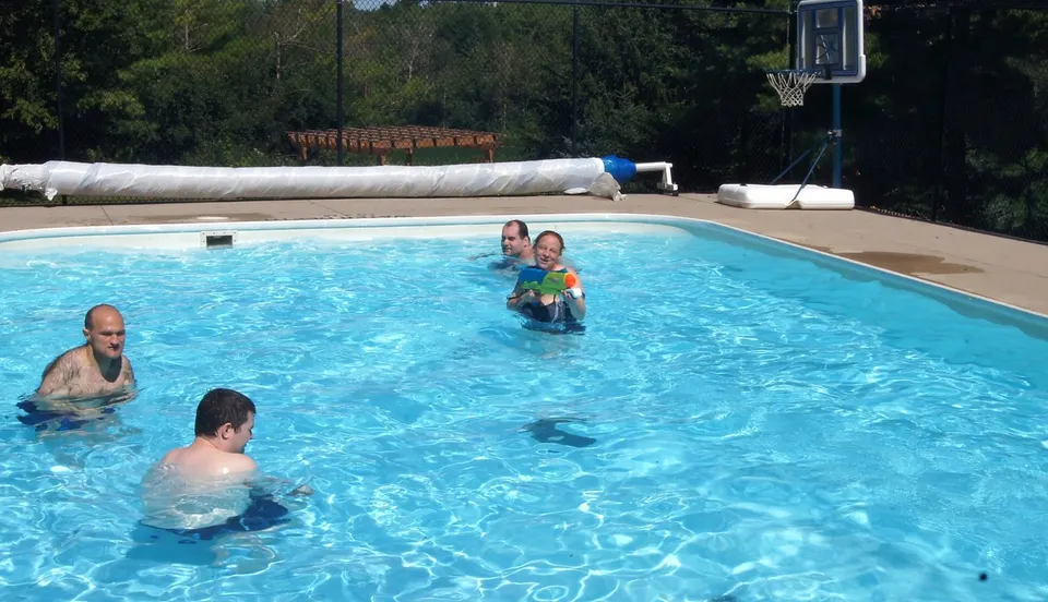 Adults and support staff enjoying the pool together on a sunny day