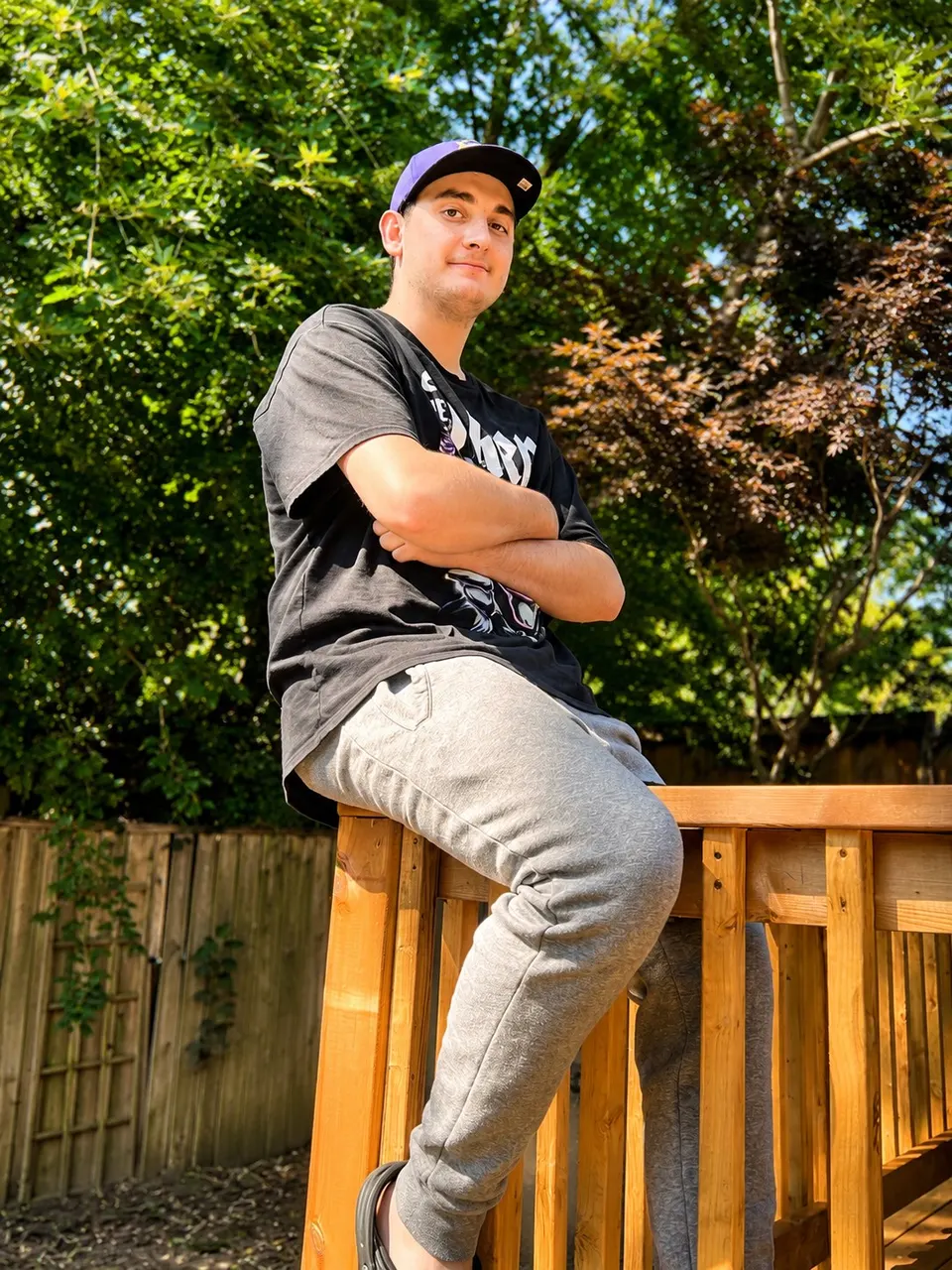A young man sitting on the sunlit deck rail outside his Hopewell home