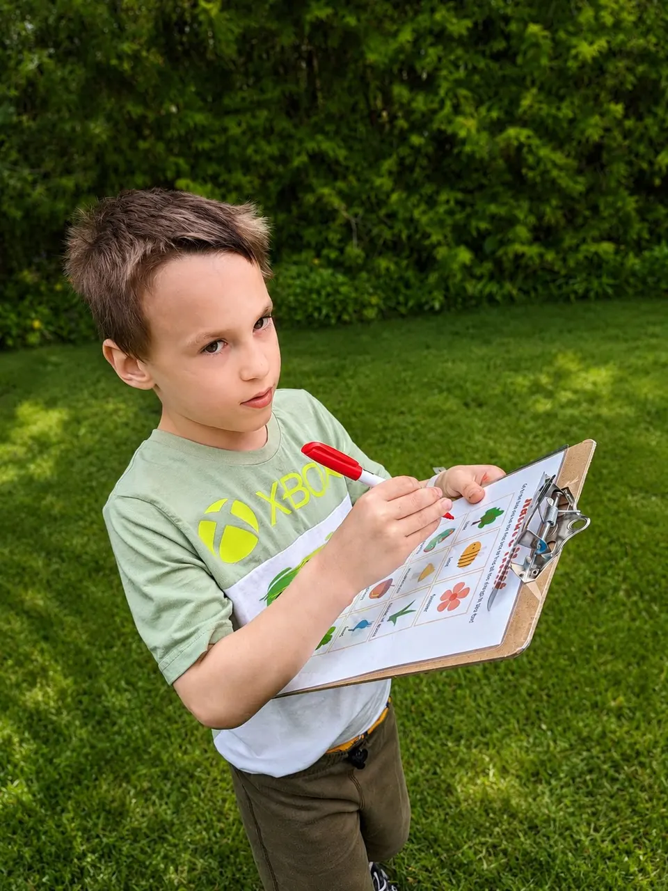 A boy working through an activity sheet on a clipboard outdoors at a youth program