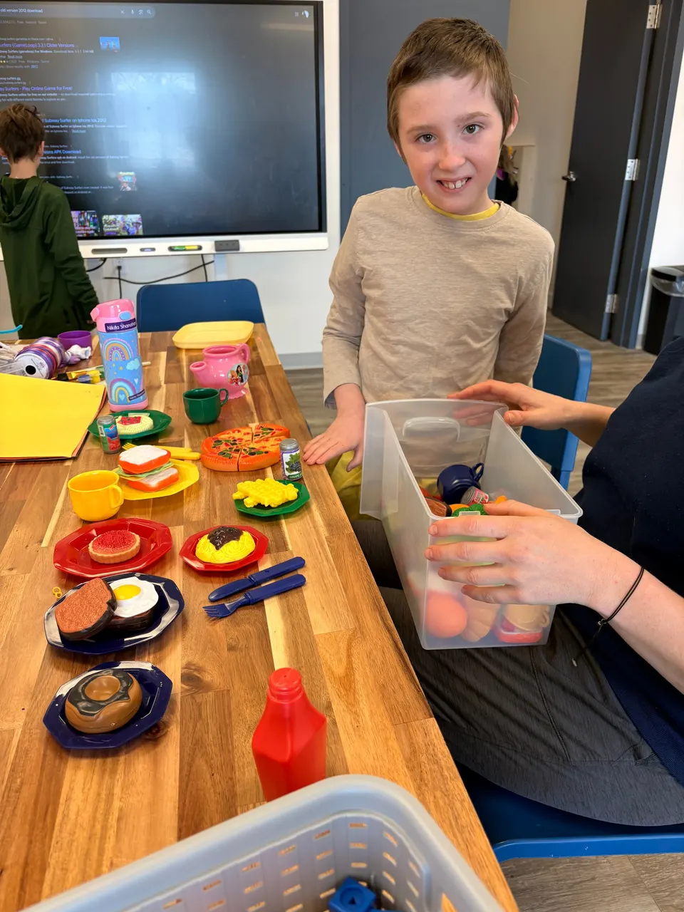 A girl swirling pink and white foam in a bin during a hands-on art activity at Youth Connect.