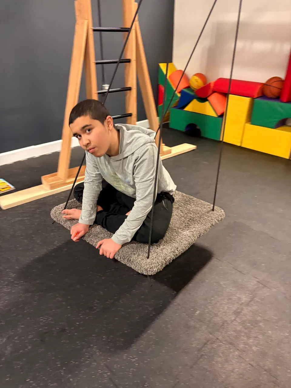 A teenager riding a platform swing in the Youth Connect sensory gym.